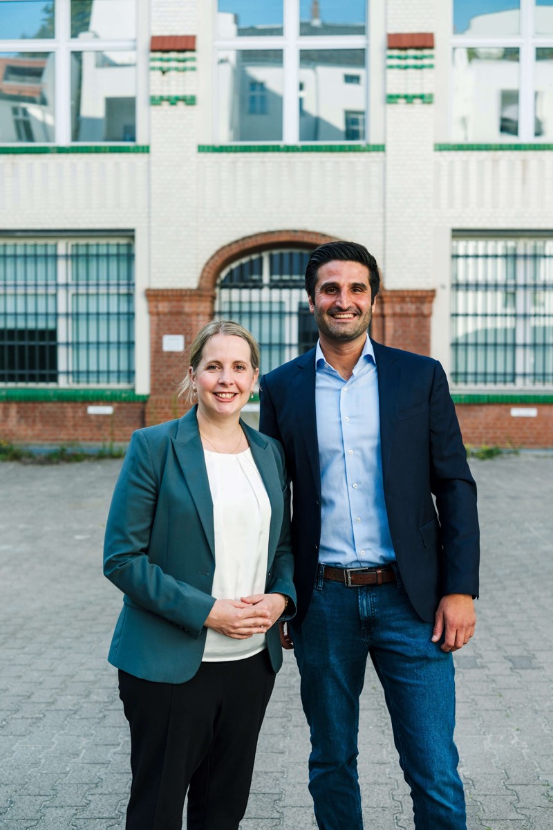 Politikerporträt: Kandidat und Kollegin vor historischer Fassade